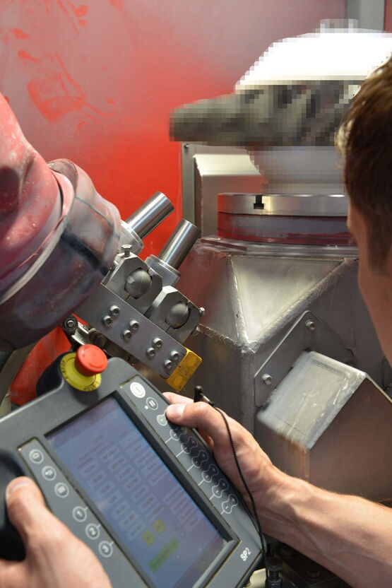 Mann bei Roboterprogrammierung am zu strahlenden Bauteil